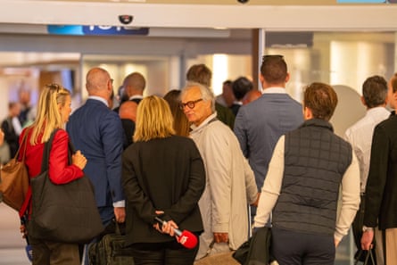 An older white man seen from behind as he turns to talk to a woman in a crowd entering a building