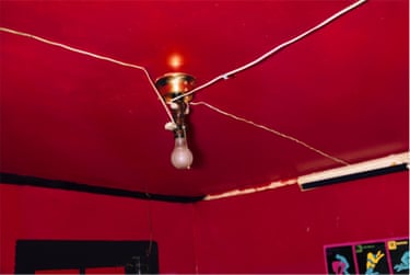 A red ceiling and red walls, with cracks in the ceiling and a bare lightbulb hanging down from a bronze fitting.