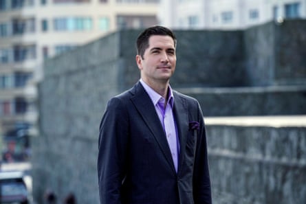 man in a suit with a concrete wall behind him