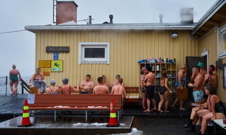 People in swimming gear standing and sitting outside the sauna at Rauhaniemi