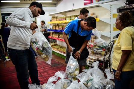 People check bags of foodstuff inside one of the food distribution centres, which have been set up by local ­committees ‘for supply and ­production’ in Caracas. 