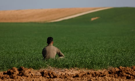An Israeli soldier sits in a field near the Israel-Gaza border.