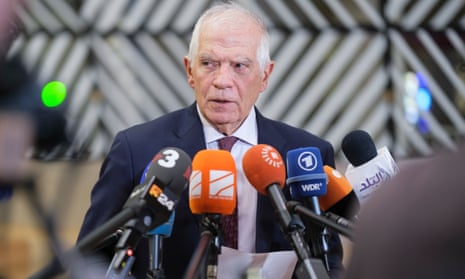 Josep Borrell stands behind a row of microphones