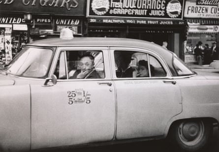 Taxicab driver at the wheel with two passengers, NYC, 1956.