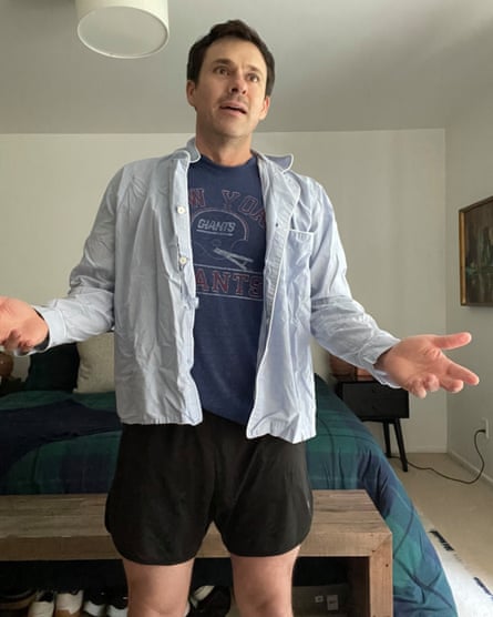 Bryan Safi in black shorts and a blue T-shirt, with a rumpled light blue shirt worn open on top.