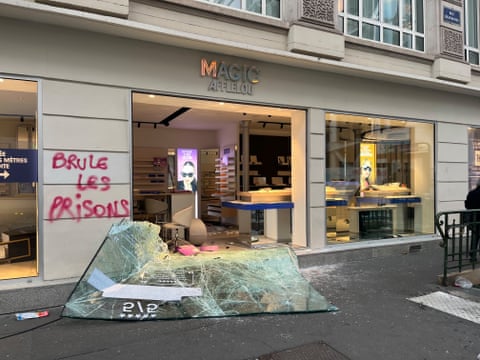 The looted shop with smashed glass outside and graffiti in red paint