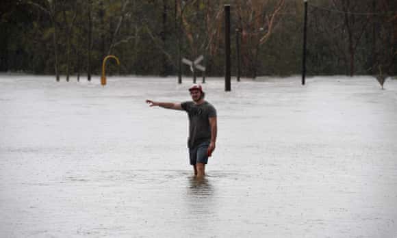 A local wades into flood waters blocking the road between Airlie Beach and Proserpine after Cyclone Debbie