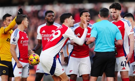 Arsenal players confront referee Michael Oliver after he showed Myles Lewis-Skelly a red card