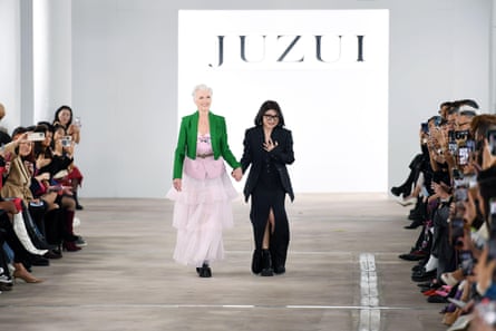 Maye Musk and Taoray Wang walk down the runway as the audience lean in to take pictures of them