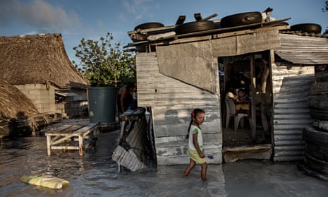 A young girl wades through the incoming sea water that flooded her house and village in Kiribati.