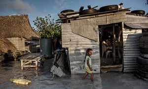 A young girl wades through the seawater that flooded her house and village
