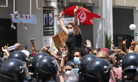 A Tunisian protester lifts a national flag at an anti-government rally