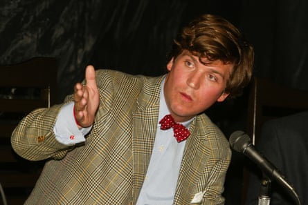A young man in a suit and bow tie leans into a microphone