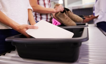 People putting items in trays for airport security check