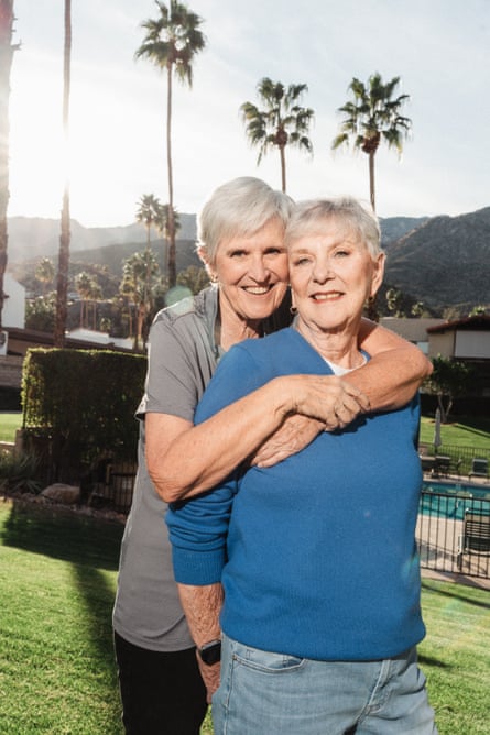 Bonnie March (in blue sweater) with her partner Cheryl Ford (interviewed below). They are photographed embracing with palm trees and mountains in the distance