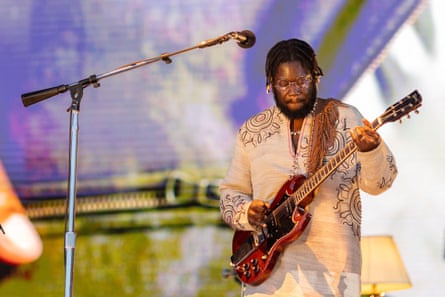 A man on stage playing a guitar with a mic stand in front of him