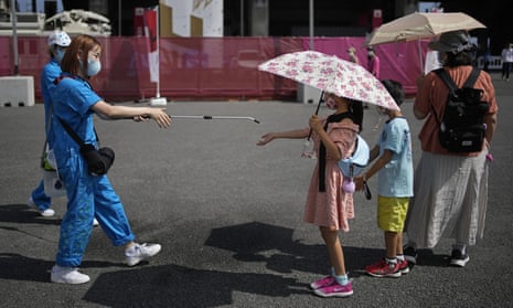 A volunteer sprays water on children as they use umbrellas to beat the heat outside the Fuji International Speedway