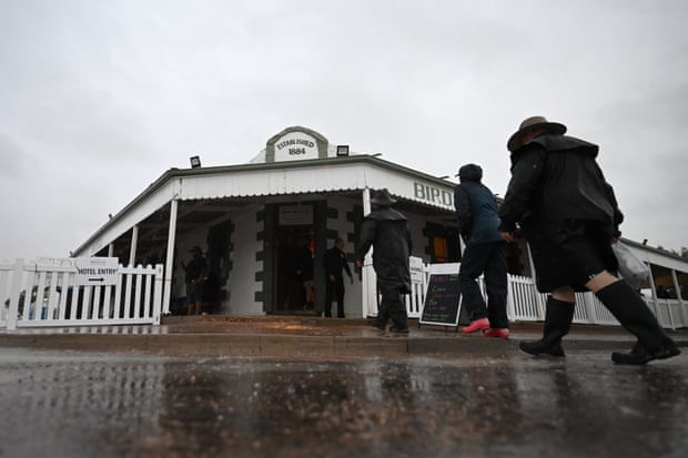 People are seen walking through the rain and into the Birdsville pub