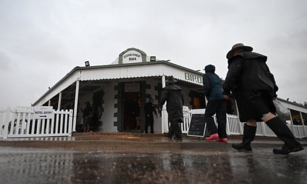 People are seen walking through the rain into the Birdsville Pub in Queensland