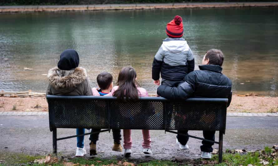 Welcome to Britain … now what? Afghan families on their lives in limbo | Refugees 2 Former Foreign Office worker Ali (not his real name), sitting on a bench with his wife and children, backs to the camera