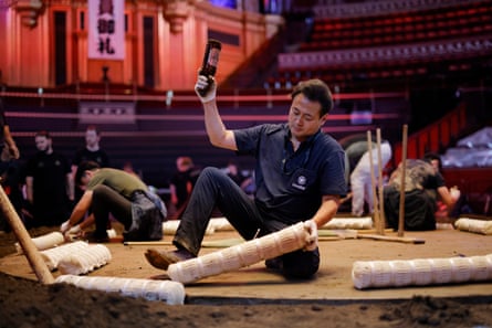 A yobidashi wields a used Asahi beer bottle to hammer the tawara into place.