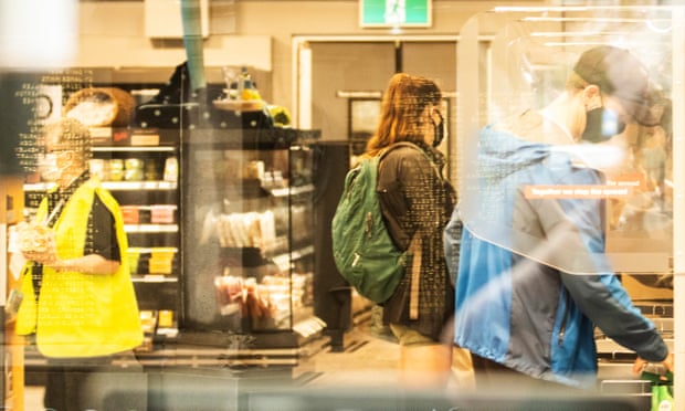 Shoppers are seen at a partitioned supermarket checkout in Manly
