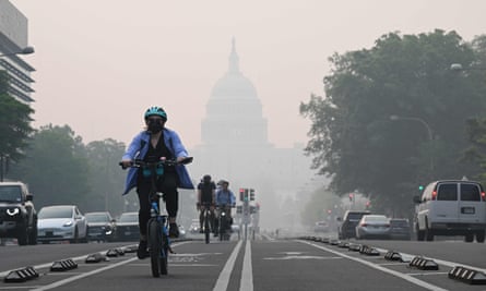 A cyclist rides under a blanket of haze partially obscuring the US Capitol in Washington, DC.
