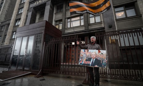 A man holds a banner that reads “We are with him. And you? For the sovereignty of Russia” outside the Russian State Duma building in Moscow after lawmakers approved the annexation of four Ukrainian territories into Russia.