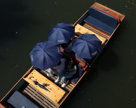 People on a punt on the River Cam in Cambridge shelter from the heatwave under umbrellas.