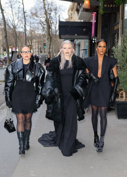 three women dresses in all black walk down the street