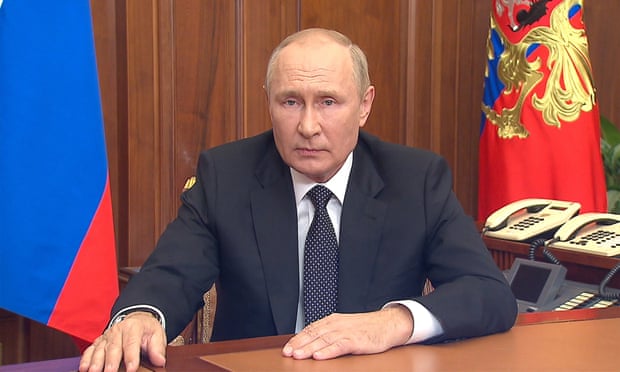 Vladimir Putin announces the mobilisation plan from his desk with flags in the background