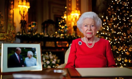 Queen Elizabeth II sitting at a desk with Christmas decor in the background