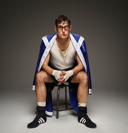 Louis Theroux sitting down wearing boxing clothes and with bandages on his hands