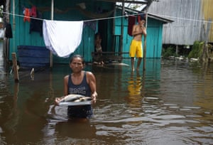 Iranduba, Brazil. Edileuza Pereira da Silva carries a plate of fish for cooking outside her home, flooded by the rise of the Negro river in Amazonas state. The Amazon region is being hit hard by flooding, with 35 municipalities facing their worst floods in years, and the water level is expected to rise over the coming months