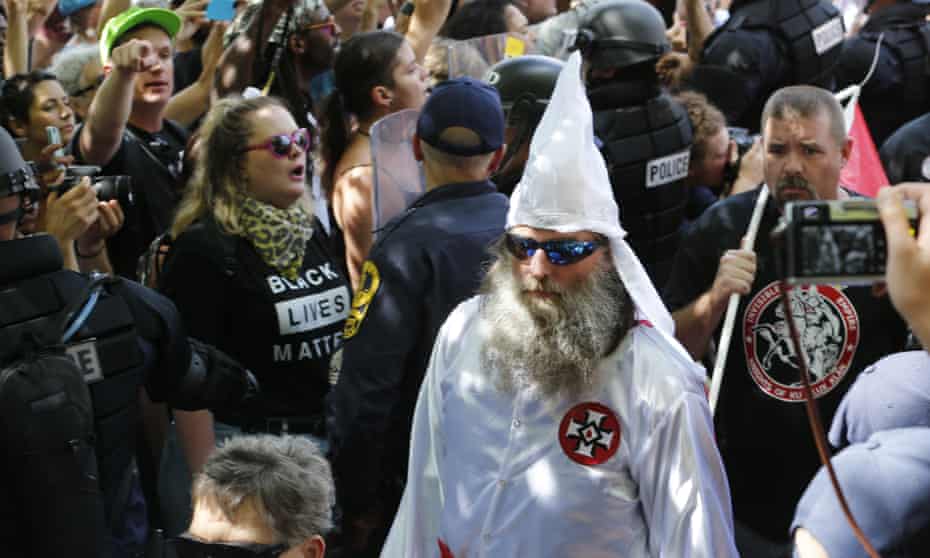 Members of the KKK are escorted by police past a large group of protesters during a KKK rally in Charlottesville, Virginia, in July this year.