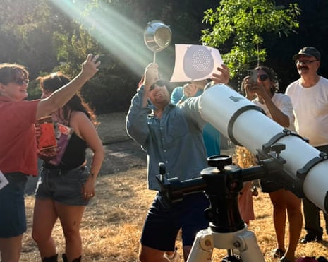 People watch the solar eclipse through a colander in a south London park
