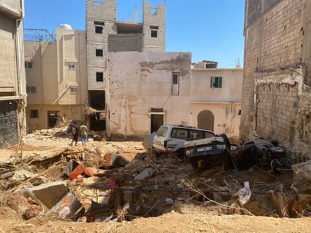 People walk amid the wreckage, in the aftermath of the floods in Derna, Libya.