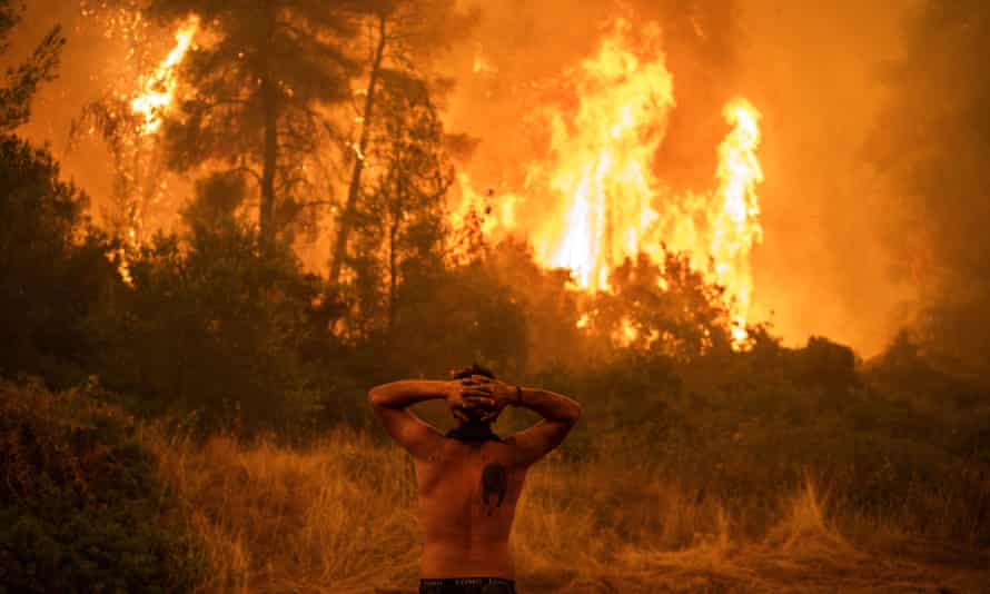 A local resident reacts as he observes a large blaze during an attempt to extinguish forest fires approaching the village of Pefki on Evia island, Greece’s second largest island