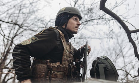 ukrainian soldier in a helmet riding a tank with a gun