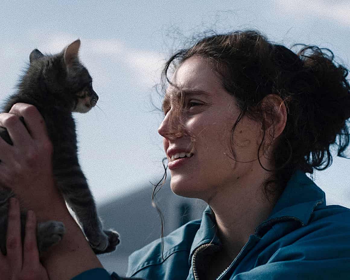 Eva Victor holds up a cat and looks into its face