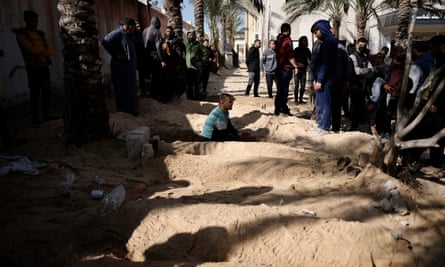 فلسطينيون يحفرون قبورًا في مستشفى ناصر لدفن أقاربهم الذين قتلوا في الهجمات الإسرائيلية.