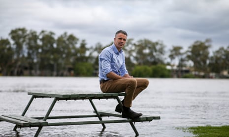 Malinauskas sits on a partially submerged picnic table at the edge of the swollen Murray River