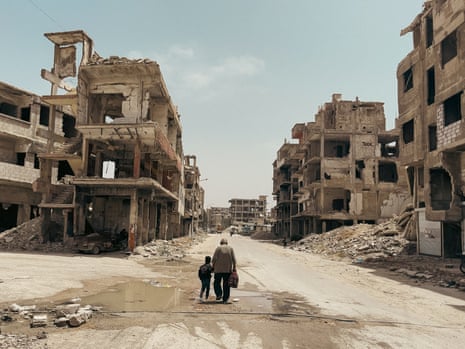 Residents of Homs walk among the ruins of the city.