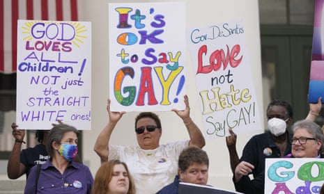 Demonstrators on the steps of the Florida state capitol building hold up signs in support of LGBTQ+ people. The one in the center reads, "It's OK to say gay!"