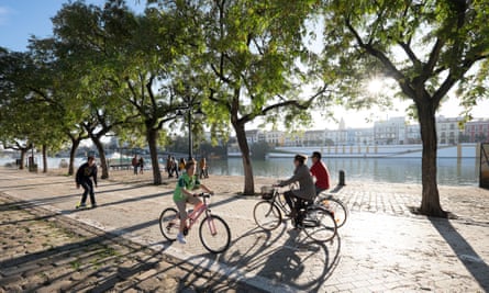Cyclists riding along the banks of the Guadalquivir river.