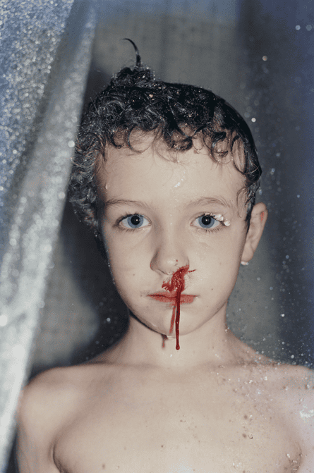 Lawrence in the shower stares at the camera as his bleeds