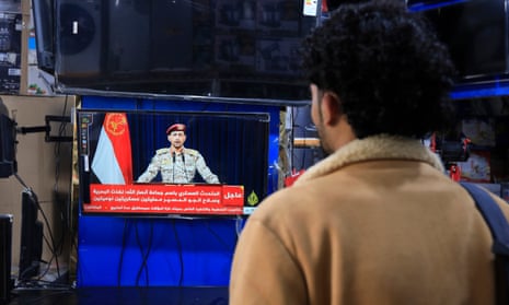 A man watches Yahya Sarea on a television screen