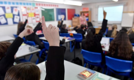 Pupils raise their hands in a lesson 