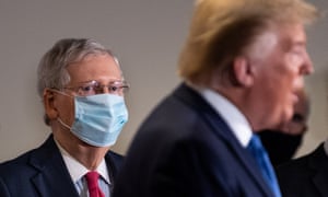 The Senate majority leader, Mitch McConnell, wears a mask as he listens to Donald Trump, who by contrast goes uncovered.