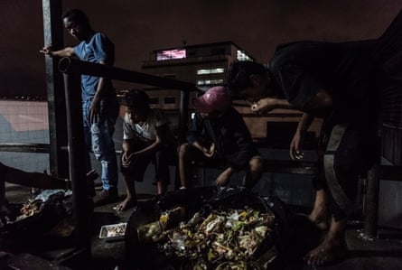 Children look for food in a rubbish dump in an alleyway behind a large shopping centre. According to Cáritas, 53% of families have had to look for food in unconventional places, often meaning among rubbish.